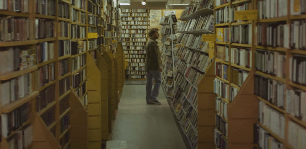 Man wandering the isles of a video store in Beyond the Gates