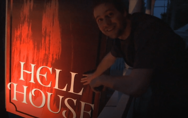 Man smiling pointing to a sign that says Hell House