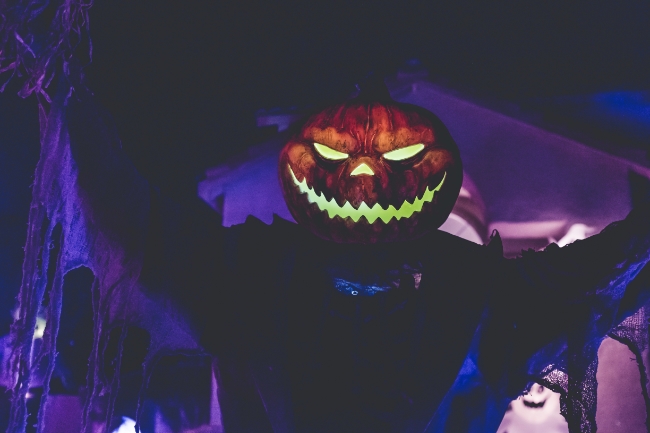 scarecrow with a lit Jack-o-lantern head