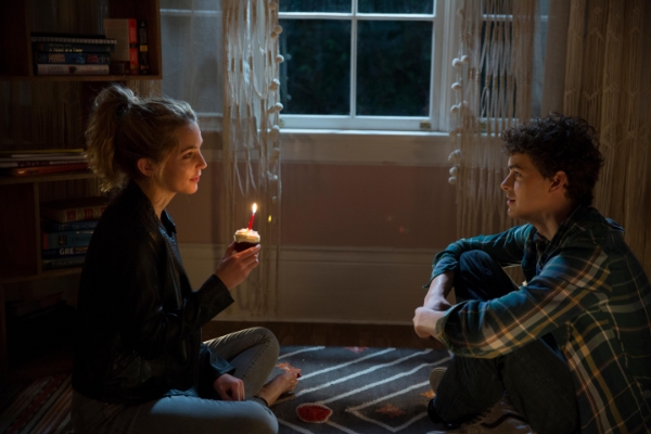 Girl holding a cupcake with a candle while a boy looks on in Happy Death Day