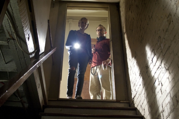 Two people looking down the stairs of a basement in The Innkeepers