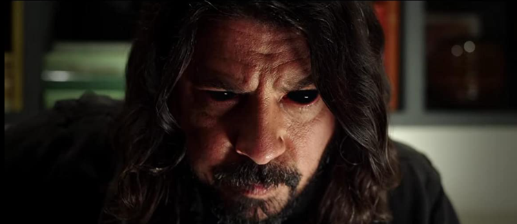 Photo of Foo Fighters frontman Dave Grohl (long dark hair, beard, wearing a black t-shirt) wearing black full-coverage FX contact lenses to look demon-possessed in Studio 666 2022